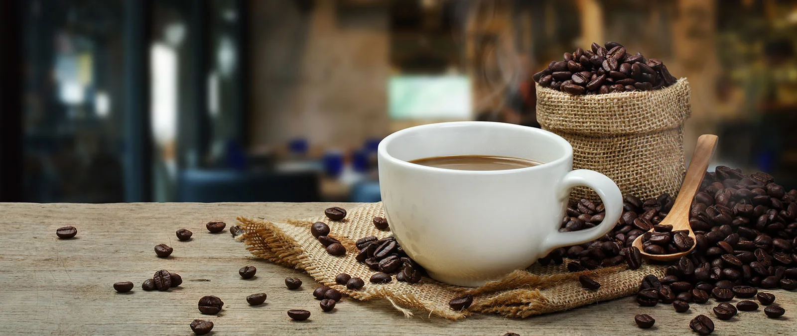A cup of coffee surrounded by coffee beans